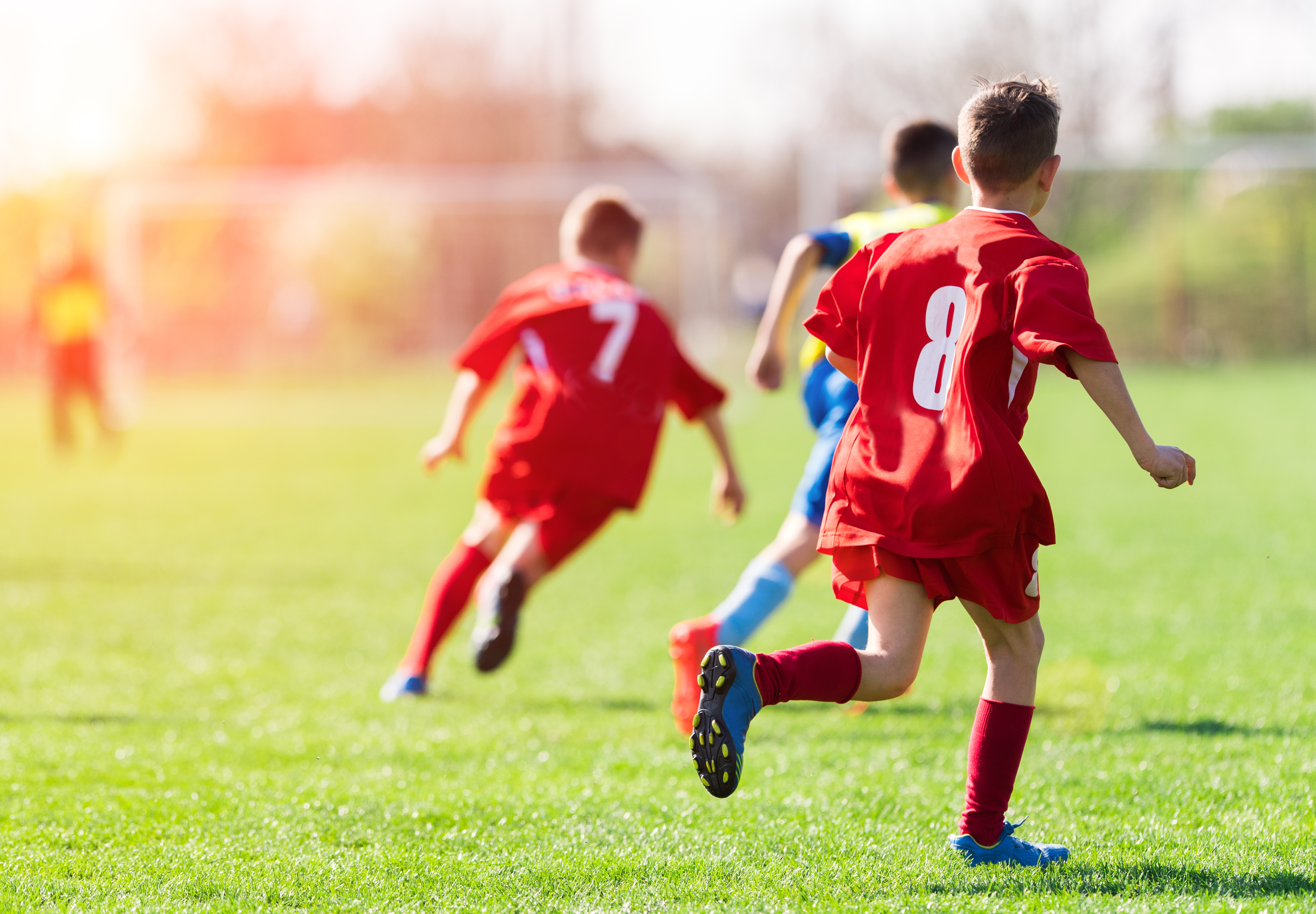 Kids playing football on a pitch outside