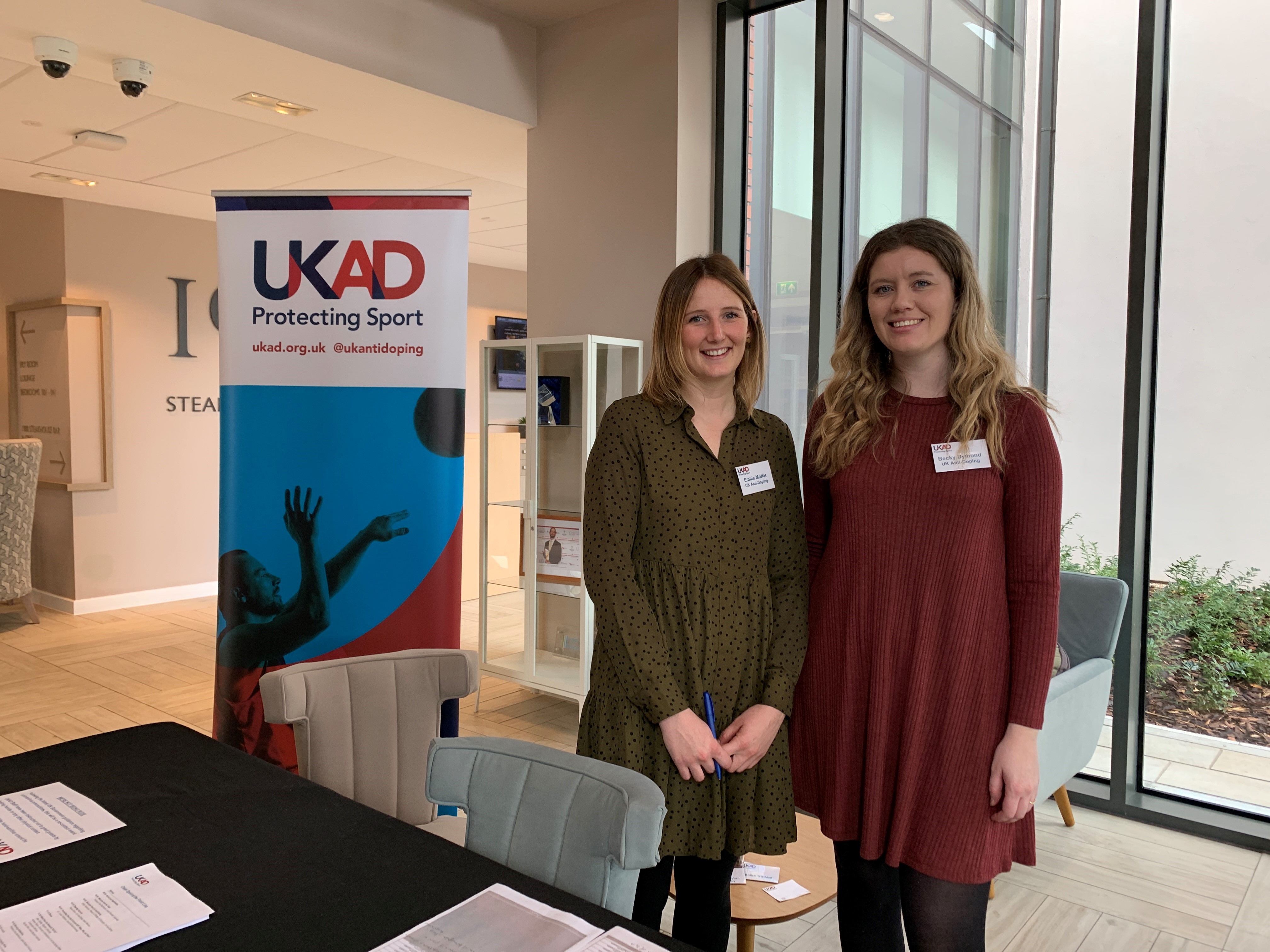 Two event organisers posting for a photo next to UKAD banner