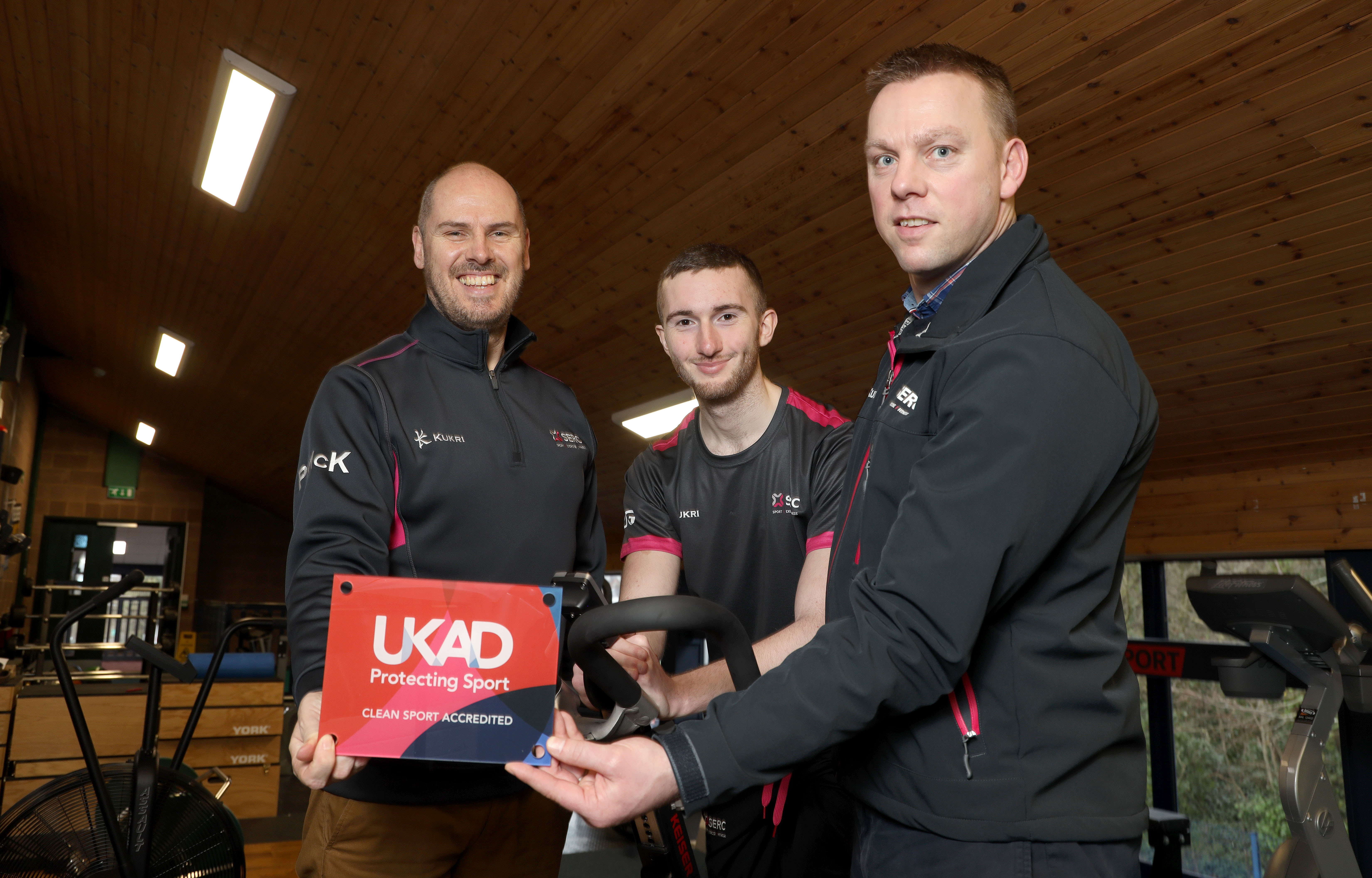 Three people smiling at camera with an award