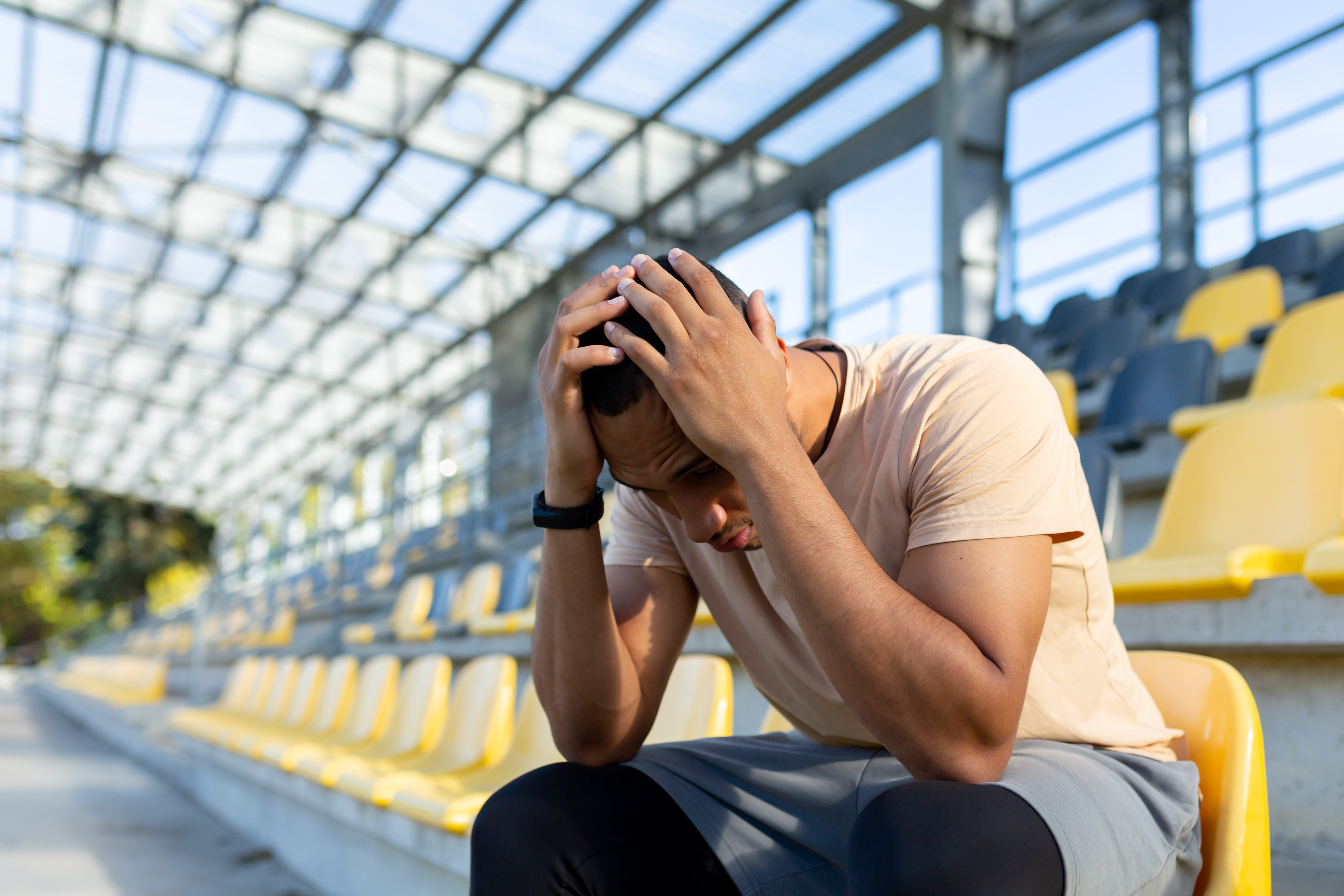 Man sat on chairs with head in hands looking stressed